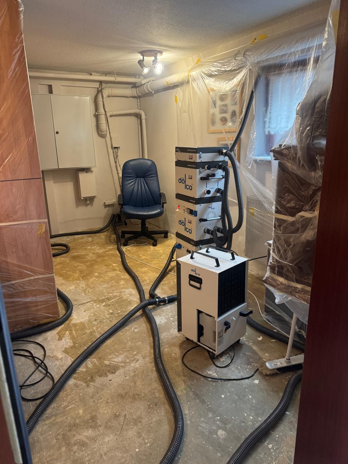 Kondenstrockner von dölco mit Wassertank vor einer Trocknungsanlage im Keller